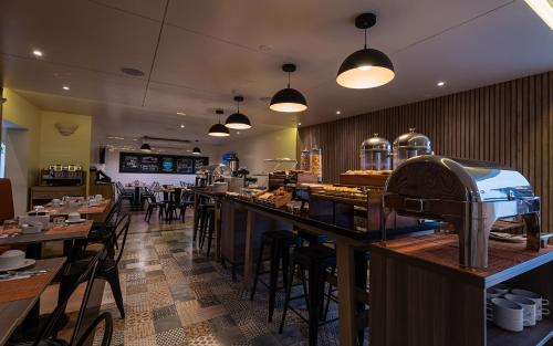 a restaurant with a bar and tables and chairs at Casa Andina Standard Trujillo Plaza in Trujillo