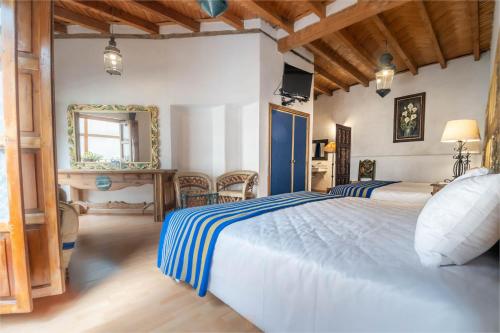 a bedroom with a large white bed with blue stripes at Hotel Rincon de Josefa in Pátzcuaro