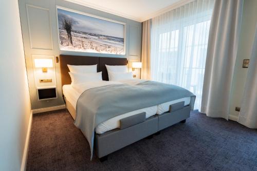 a bedroom with a large bed with a painting on the wall at Hotel Strandperle in Cuxhaven
