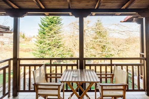 - une table et des chaises en bois sur une terrasse couverte dans l'établissement hostel lake plastira, à Kalyvia