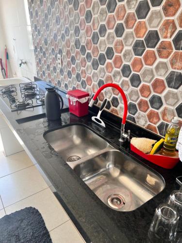 a kitchen sink with a red faucet in a kitchen at Apartamento 2 quartos mobiliado in Três Lagoas