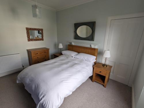 a bedroom with a large white bed and a mirror at Sandstones in North Berwick