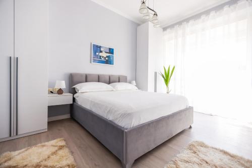 een witte slaapkamer met een groot bed en een raam bij Viewpoint Central apartment in Tirana