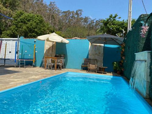 a blue swimming pool with a table and an umbrella at Residencial Águas de Bare in São Sebastião