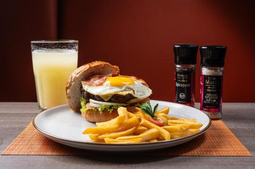 a plate with a sandwich and fries and a glass of orange juice at Casa Andina Standard Trujillo Plaza in Trujillo