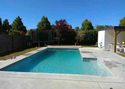 una piscina con acqua blu in un cortile di Chambre et salle de bain privatives a Bénesse-Maremne