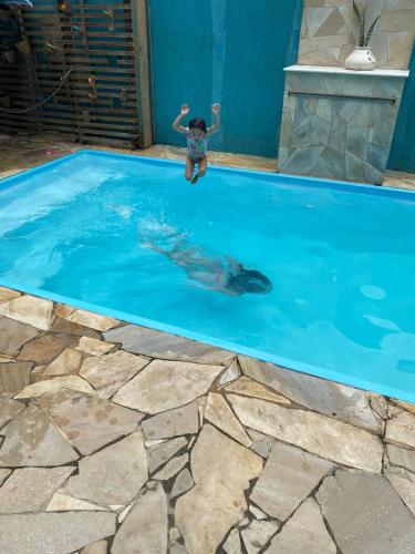 a person in a pool with a dolphin in the water at Residencial Águas de Bare in São Sebastião