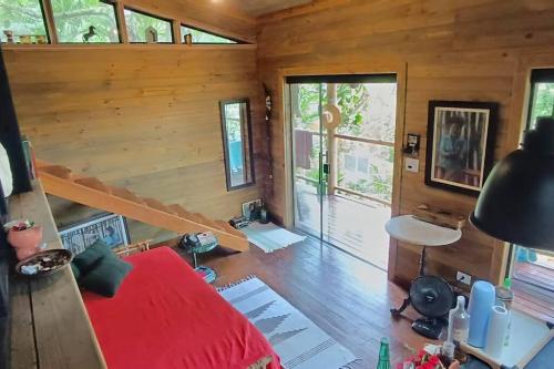 een slaapkamer met een rood bed in een houten kamer bij Eco Cabana a 150 metros da praia e centrinho in Paraty