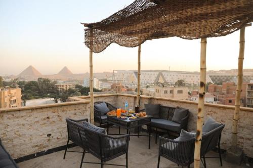eine Terrasse mit Stühlen und einem Tisch mit Blick auf die Pyramiden in der Unterkunft King Tout Hotel Pyramids view in Kairo