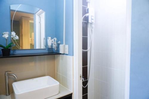a bathroom with a sink and a shower with a mirror at ALTEAN Apartments - Lydia Room in Manila