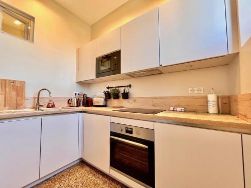 a kitchen with white cabinets and a stove top oven at Appartement bourgeois avec terrasse et vue lac in Aix-les-Bains
