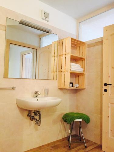 a bathroom with a sink and a green stool at Baita del Beniamino in Roncegno