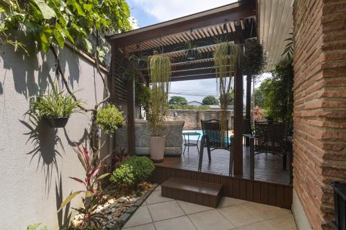 um pátio com uma mesa, cadeiras e plantas em Casa com churrasq, piscina e Wi-Fi em Criciuma SC em Criciúma