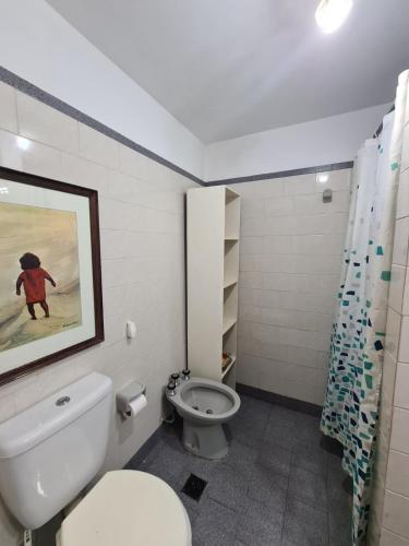 a bathroom with a toilet and a painting on the wall at Duplex 300 m del mar Barapoint in Necochea