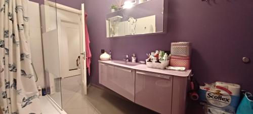 uma casa de banho com um lavatório e uma parede roxa em Robby's Room em Reggio Emilia