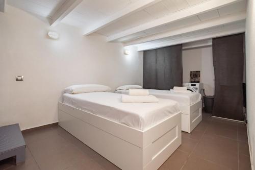 Modern and bright 4BD triplex in Paralel! في برشلونة: سريرين في غرفة بجدران بيضاء