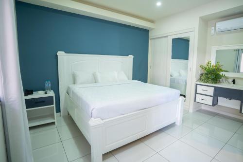 1 dormitorio con cama blanca y pared azul en Hotel Mar Azul 