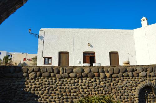 un edificio blanco con puertas marrones y una pared de piedra en The Lady of Flakopi, en Pachaina