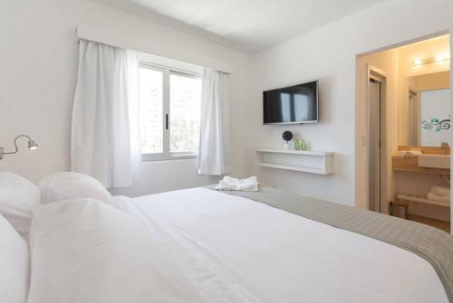 a white bedroom with a bed and a television at 20 Hotel in Punta del Este