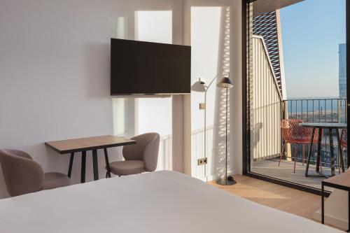 a bedroom with a bed and a balcony with a tv at Tembo Barcelona in Barcelona