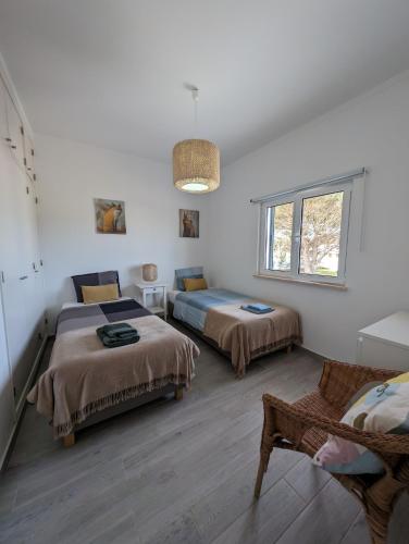 a white room with two beds and a window at Casa Oliveira in Sagres