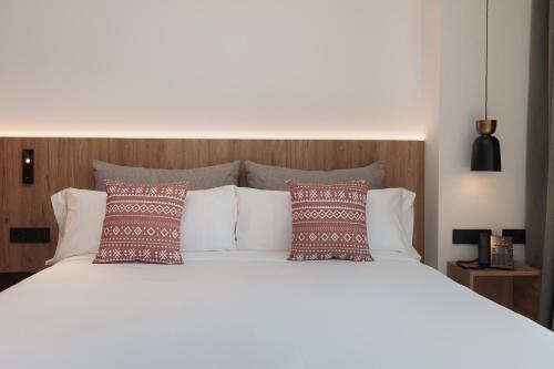 a bedroom with a white bed with red and white pillows at Tembo Barcelona in Barcelona