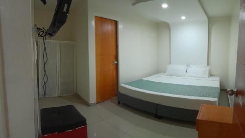 um pequeno quarto com uma cama e uma porta de madeira em AW Connect Airport em Bogotá