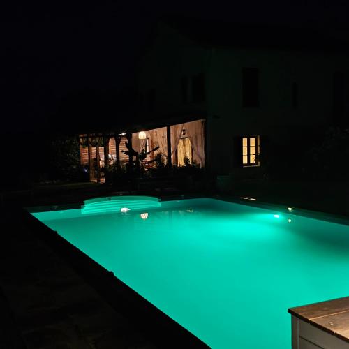 a swimming pool at night with blue lights at Maison rénovée typique, au calme, piscine. in La Courtète