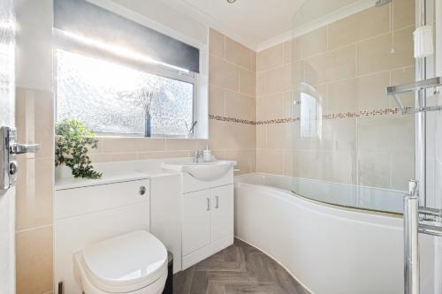 ein Badezimmer mit einem WC, einem Waschbecken und einer Badewanne in der Unterkunft Comfy Home Ideal for Groups - Free Parking in Bedford
