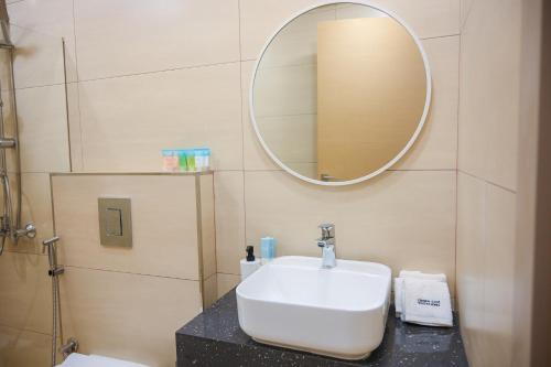 a bathroom with a white sink and a mirror at Diamond Jumeirah Garden City 1BR Apt in Dubai