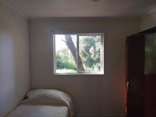 a small bedroom with a window in the corner at Cabaña Campestre in Osorno