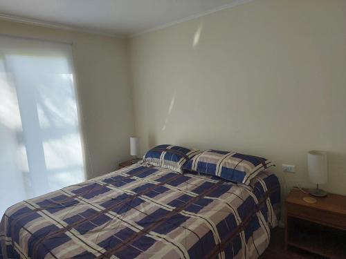 1 dormitorio con 1 cama con manta a cuadros y ventana en Cabaña Campestre, en Osorno