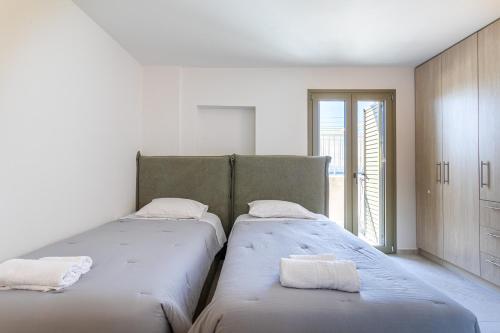 two beds in a white room with a window at Villa Daniela in Neokhórion