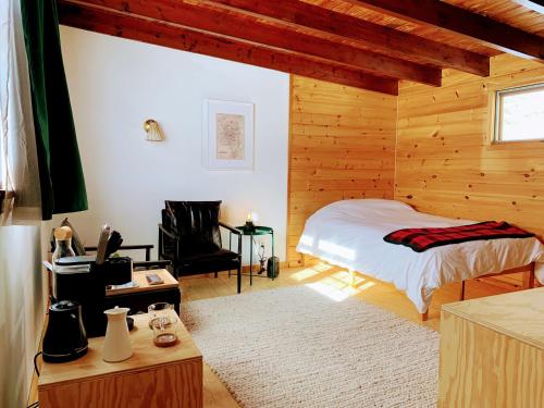 a bedroom with wooden walls and a bed and a chair at The Lorca Adirondacks Motel in Indian Lake