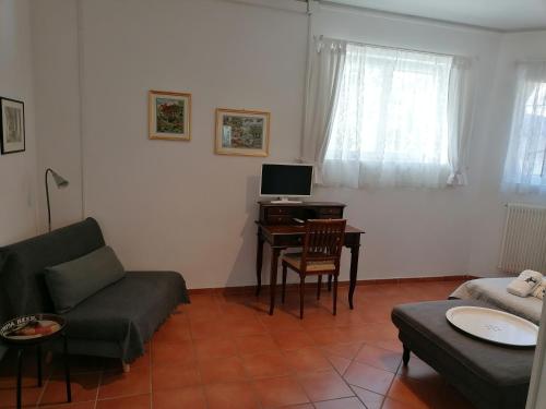 een woonkamer met een bank en een bureau met een computer bij Grazioso appartamento tra cultura, lago e montagna in Pomarolo