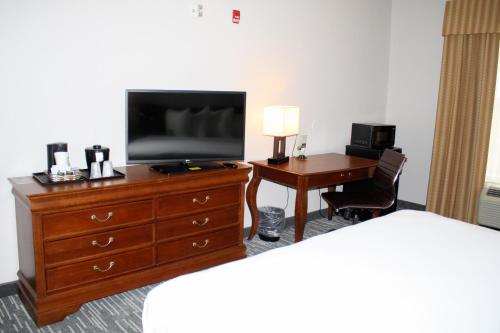 a hotel room with a television on a dresser with a desk at Country Inn & Suites by Radisson, BWI Airport Baltimore , MD in Linthicum Heights