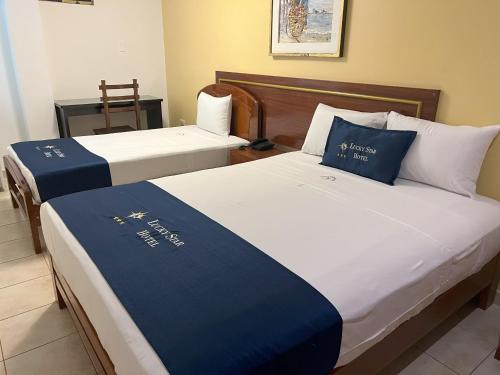 two beds with blue and white sheets in a room at Lucky Star Hotel in Chiclayo