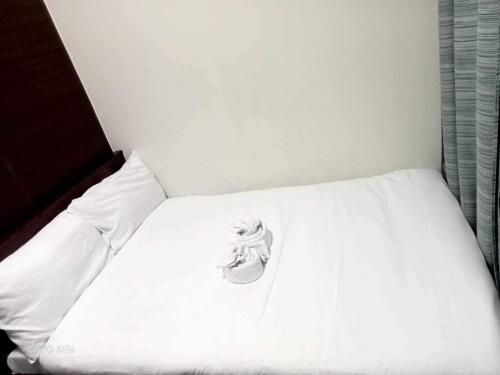 ein weißes Bett mit einem Schuh darüber in der Unterkunft Air Residence A1 Central Makati Business District in Manila