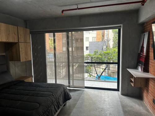 a bedroom with a bed and a large sliding glass door at Apartaestudio tipo loft nuevo in Medellín