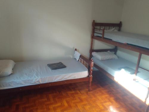 2 Etagenbetten in einem Zimmer mit Holzböden in der Unterkunft Quarto no centro de Londrina, TV, ventilador e wifi in Londrina