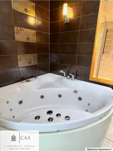 a white tub in a bathroom with a tiled wall at C Apartments Annedal in Gothenburg