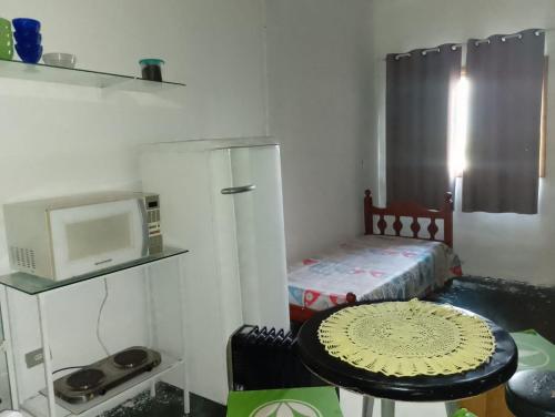 um pequeno quarto com uma mesa e um micro-ondas em Quarto e banheiro particular em Taboão da Serra