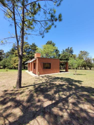 uma pequena casa num campo com uma árvore em Casas de Campo em Santa María