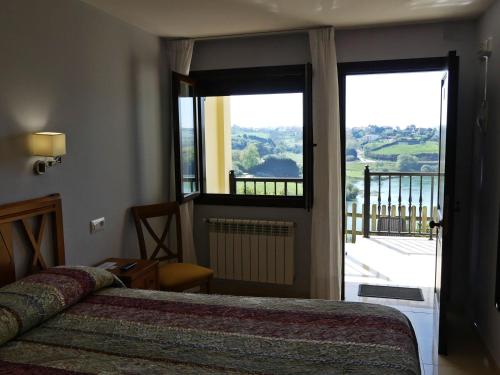 a bedroom with a bed and a large window at El Mirador de Trasvia Comillas in Trasvia