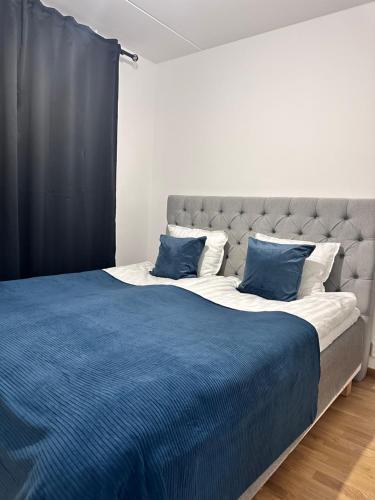 a bed with a blue blanket and two pillows at Fresh Apartment in Stockholm