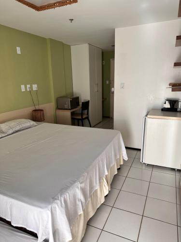 um quarto com uma grande cama branca e uma cozinha em Gran Lençóis Flat Residence em Barreirinhas