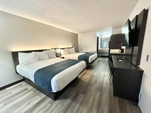 ルイスビルにあるStudio 6 Suites Louisville KY Airport/Expo Centerのベッド2台とデスクが備わるホテルルームです。