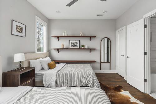 Habitación con 2 camas, paredes blancas y suelo de madera. en Modern Luxury Rooftop Deck, 3 mi to Downtown, en Nashville