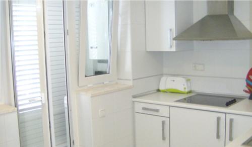 eine Küche mit weißen Schränken, einem Waschbecken und einem Fenster in der Unterkunft Dúplex en primera línea Playa Faro in Garrucha