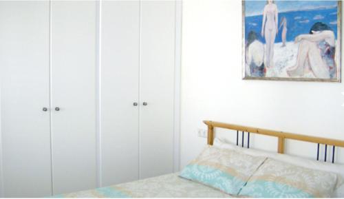 Schlafzimmer mit weißen Schränken und einem Bett mit Bild in der Unterkunft Dúplex en primera línea Playa Faro in Garrucha